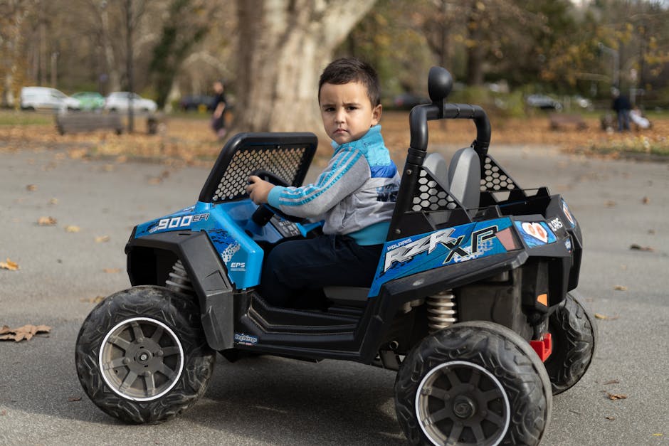A child sitting and driving an electric toy car in a park. Outdoor fun and playtime.